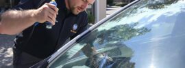 technician repairing a small crack in a car windshield using a resin injection tool.